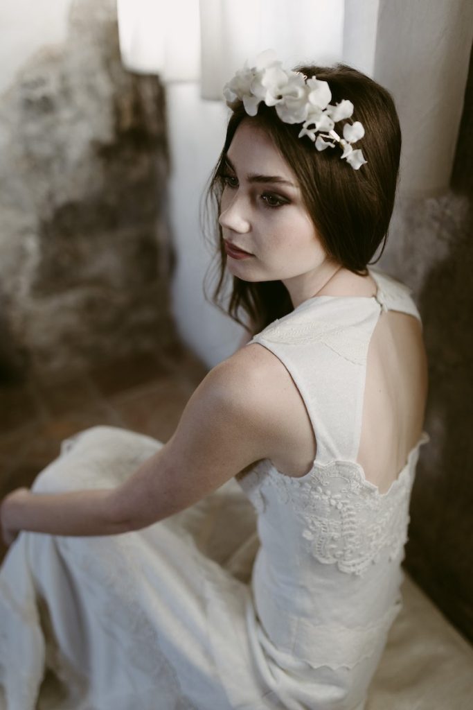 In questa foto un'acconciatura da sposa 2024 con un cerchietto di maxi fiori di colore bianco