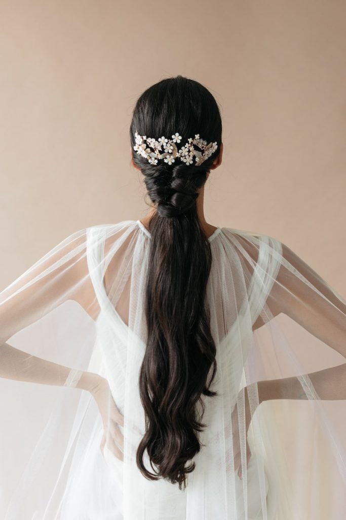 In questa foto una ponytail da sposa con treccia e un fermaglio con piccoli fiori