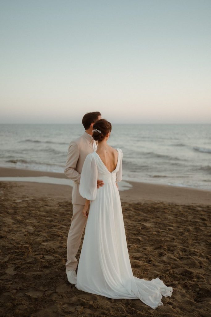 In questa foto di Alessio Bazzichi due sposi su una spiaggia e di spalle che guardano il mare