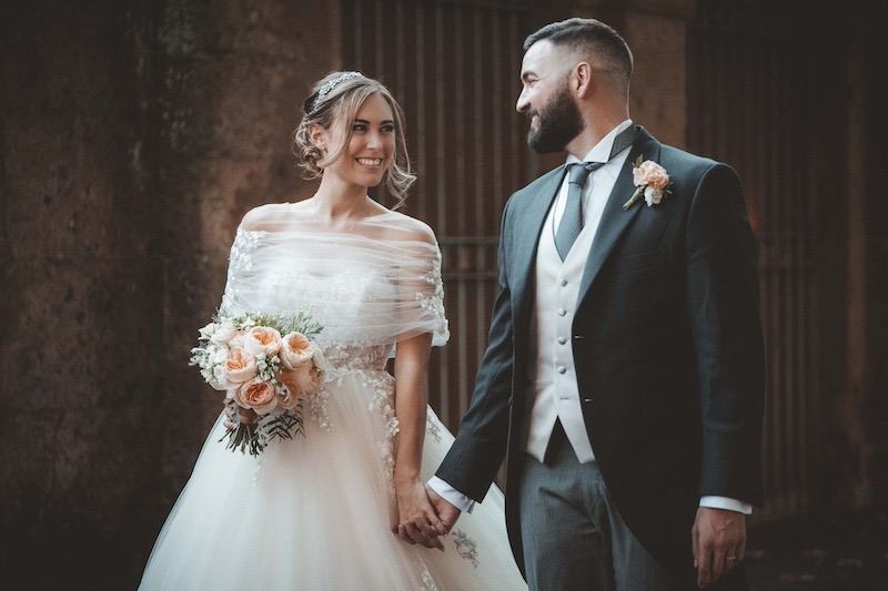 In questa foto di Emiliano Allegrezza due sposi si guardano sorridendo mentre camminano mano nella mano