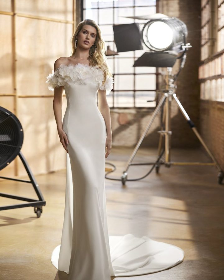 In questa foto una modella posa indossando un abito da sposa Aire Atelier 2025 a sirena con maxi fiori 3D sulla scollatura dritta