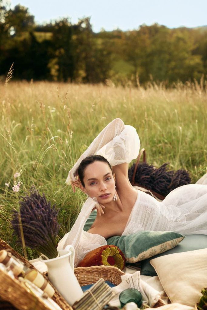 In questa foto la modella Luma Grothe posa per la nuova campagna di Atelier Emé "The Bride" indossando un abito da sposa con maniche balloon, sdraiata su un prato per un picnic