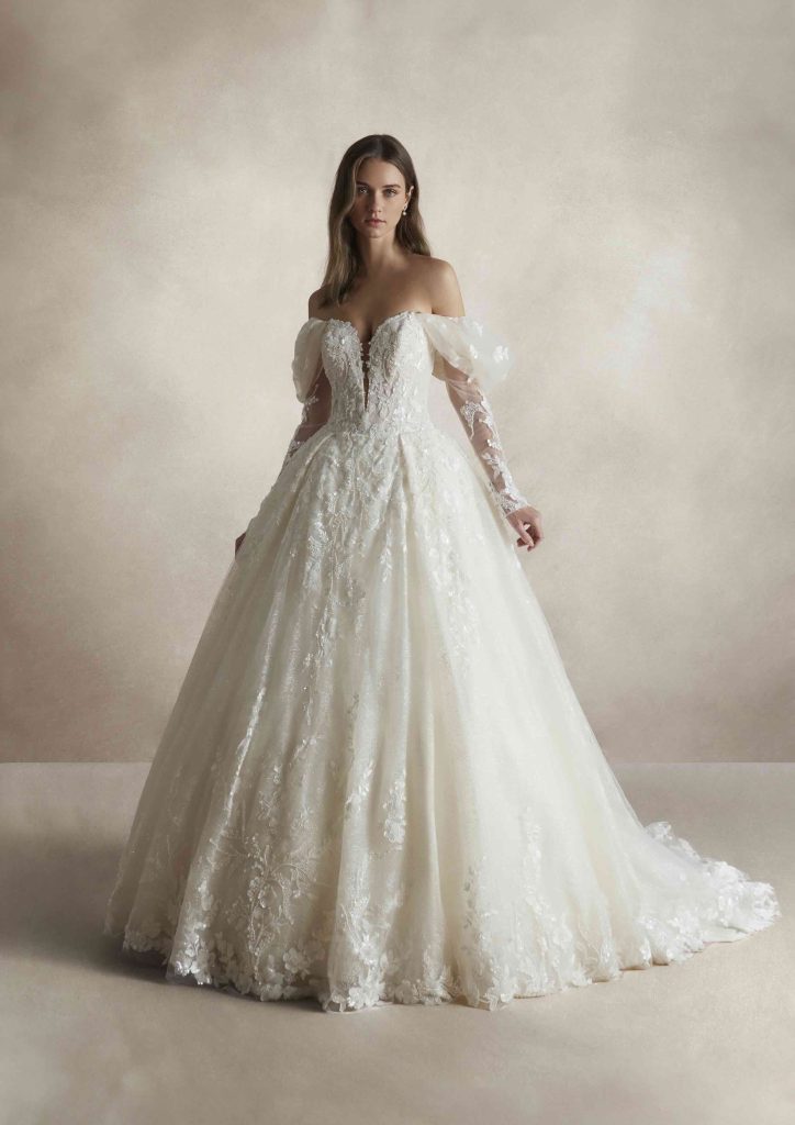 In questa immagine un abito da sposa  ampio con dettagli in pizzo di Nicole Couture. 