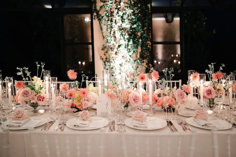 In questa foto uno dei tavoli imperiali del matrimonio di Carrie e Adam decorato da Imène Hanafi con fiori nelle grandazioni del rosa, porcellane, candele e candelabri di vetro