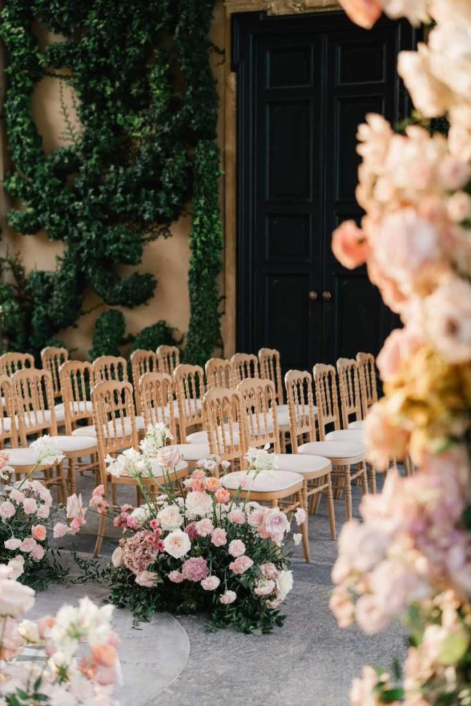 In questa foto la Loggia Durini di Villa del Balbianello allestita da Imène Hanafi per la cerimonia del matrimonio di Carrie e Adam con fiori nei toni del rosa e sedie di colore dorato 