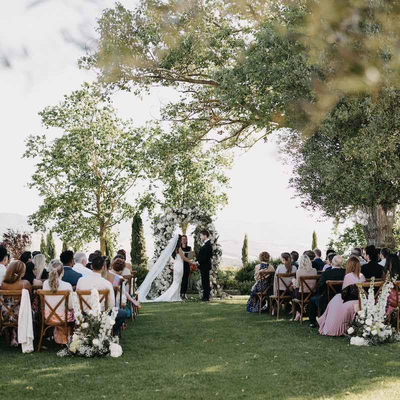 In questa foto una celebrante legge un discorso durante la cerimonia di due sposi in un giardino