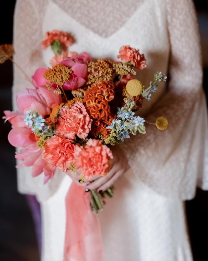 In questa foto, un bouquet da sposa dai toni vivaci del rosa e dell'arancione