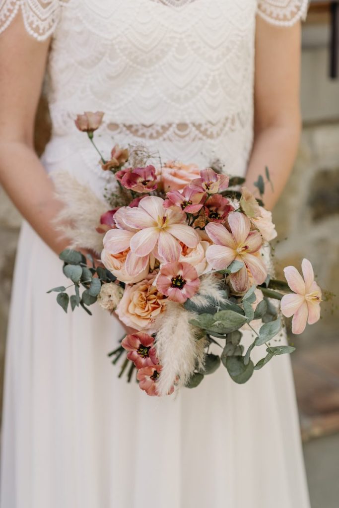 In questa foto, un bouquet da sposa 2025 con fiori nei toni del rosa cipria