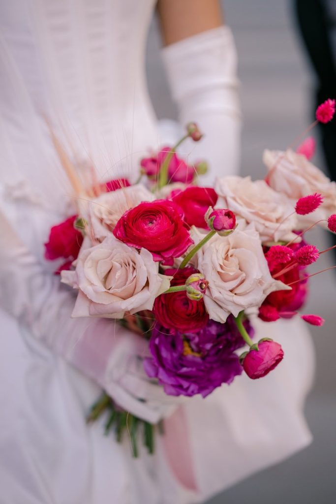 In questa foto, un bouquet da sposa 2025 nei toni del fucsia, del rosa e del viola