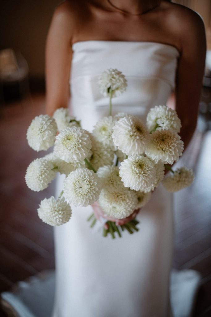 In questa foto, un bouquet da sposa 2025 con dalie di colore bianco