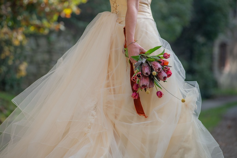 In questa foto, un bouquet da sposa 2025 nei toni del viola e del rosso