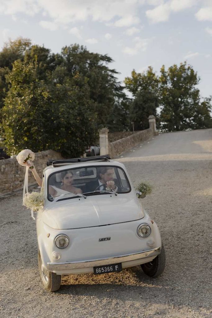 In questa foto, due sposi arrivano a Villa Corsini a bordo di una Cinquecento d'epoca di colore bianco