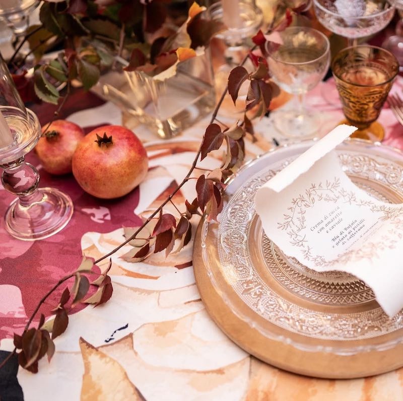 In questa foto, una mise en place per matrimonio nei toni del rosso con melograni