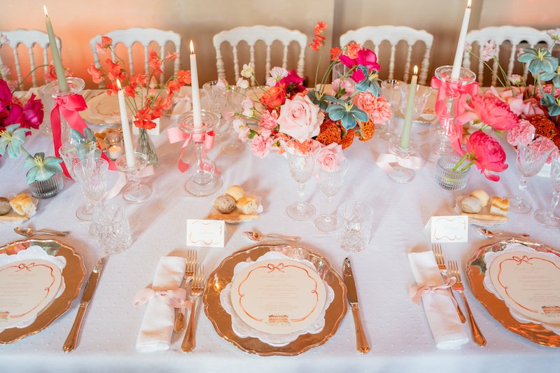 In questa foto, una mise en place per matrimonio nei toni dell'arancione, del fucsia e rosa