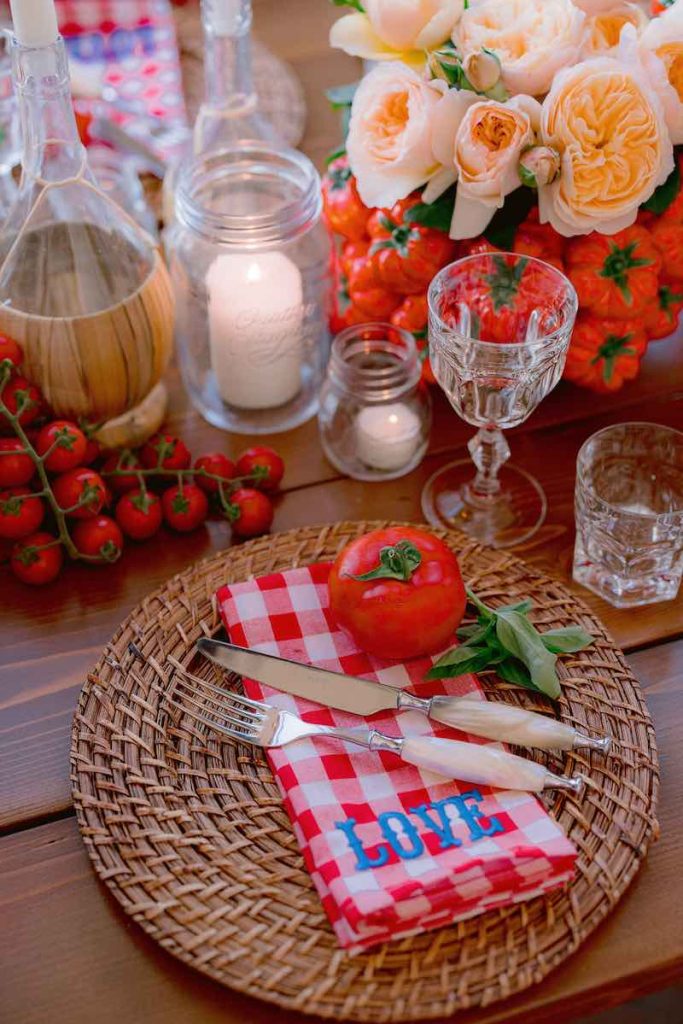 In questa foto, una mise en place per matrimonio nei toni del rosso con pomodori