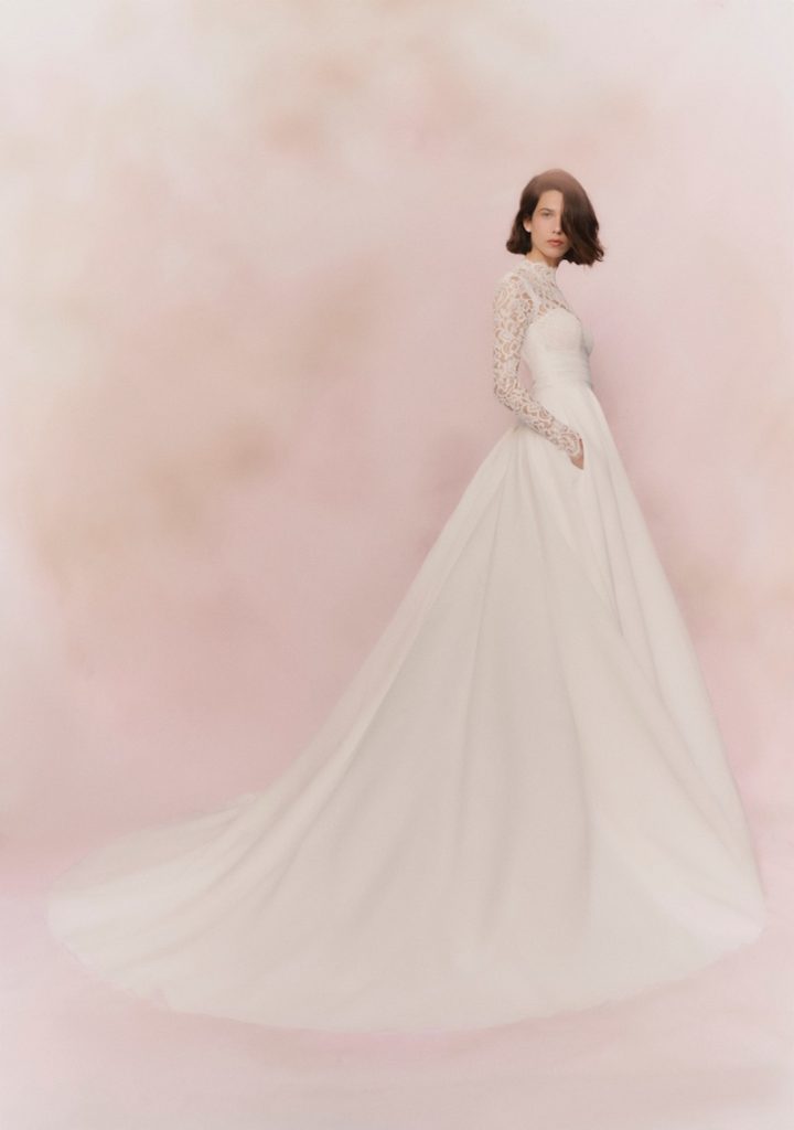 In questa foto, una modella indossa un abito da sposa principessa con gonna in organza e maniche lunghe in pizzo