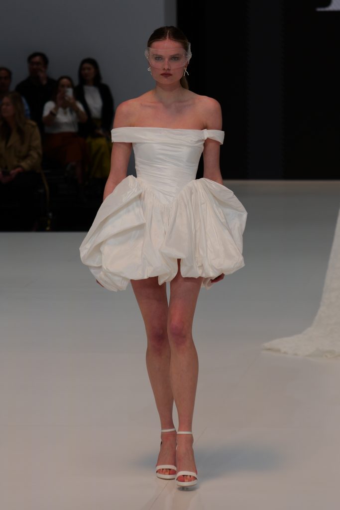 In questa foto la modella indossa in passerella un abito Ricca Sposa 2026  corto