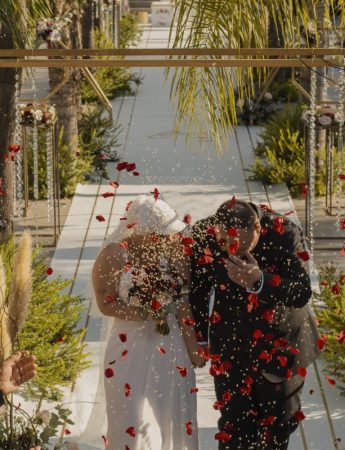 In questa foto due sposi escono dalla location del loro rito civile inondati da riso e petali di fiori